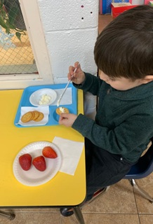 Toddler prepares his own simple but nutritious snack.